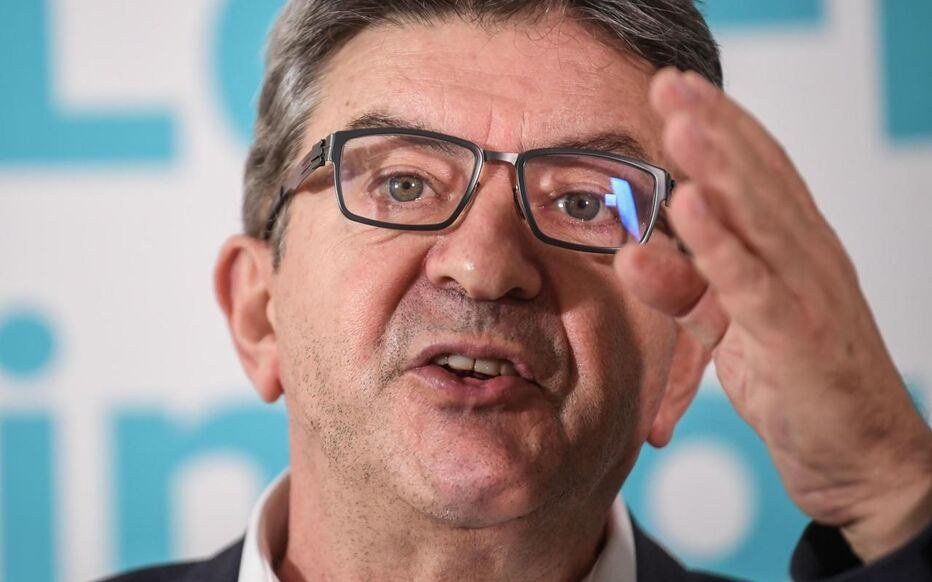 Jean Luc Mélenchon, lunettes, exprime un geste de la main en parlant.