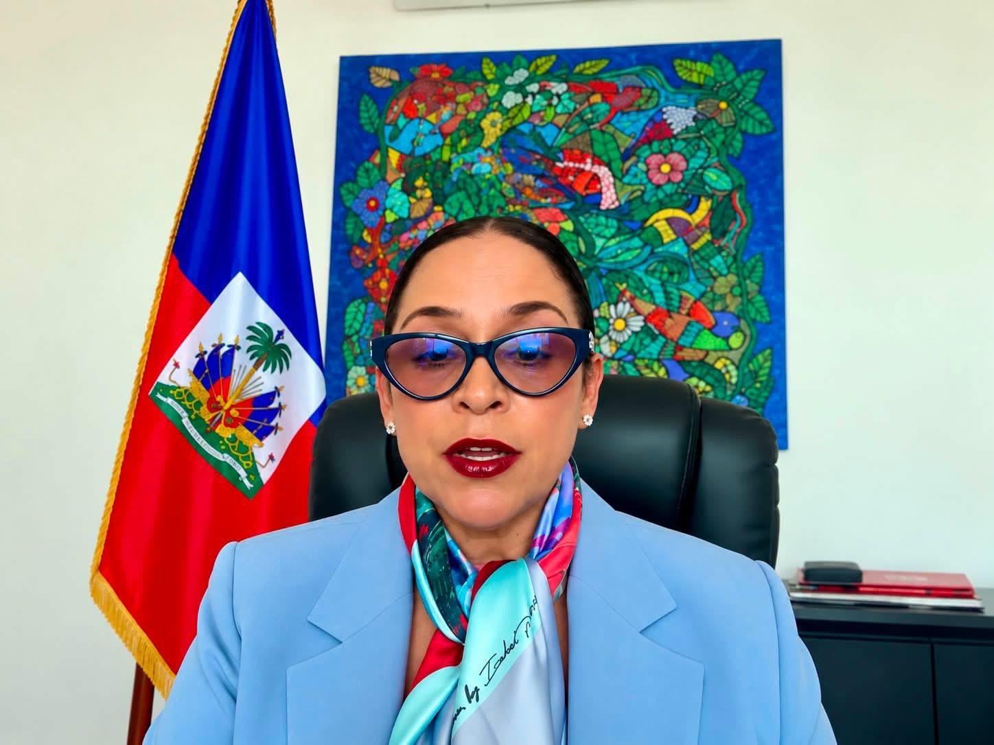 La ministre haïtienne des Affaires étrangères Raina Forbin s'exprimant en visioconférence, drapeau haïtien à l'arrière-plan.